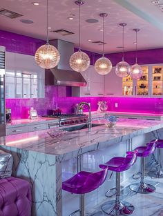 a kitchen with marble counter tops and purple stools in front of the bar area