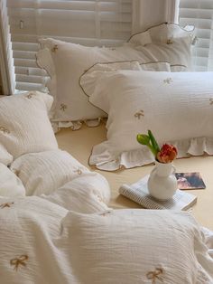 a bed with white linens and pillows on top of it next to a window