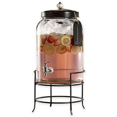 a beverage dispenser filled with liquid and sliced fruit on a metal stand