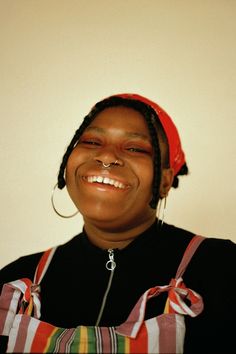 a smiling woman wearing an orange and white striped headband, with her eyes closed