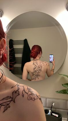 a woman with tattoos taking a selfie in front of a mirror