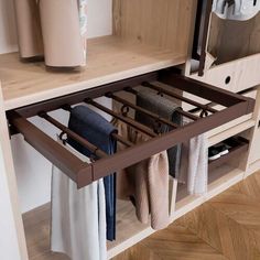 an open drawer in a kitchen with towels hanging on the bottom and towel racks below