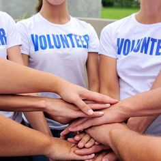 group of people holding hands together with volunteer t - shirts on