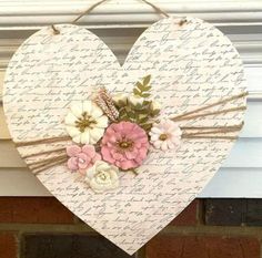 a heart hanging on the side of a brick wall with flowers and leaves in it