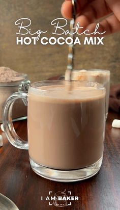 a person stirring hot chocolate in a glass mug