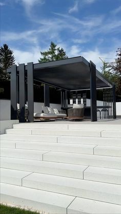 an outdoor covered area with lounge chairs and umbrellas on the steps leading up to it