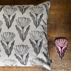 a pillow with a pink flower on it next to a small piece of fabric that has been cut in half