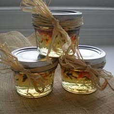 four jars filled with food sitting on top of a burlied tablecloth covered table