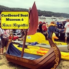 people standing around boats on the beach with a sign that says cardboard boat museum & race regatta