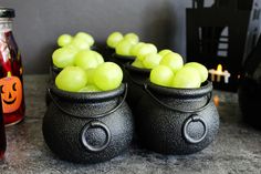 there are some black pots with green apples in them