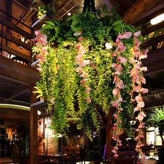 the interior of a restaurant with hanging flowers and plants on the ceiling, along with tables and chairs