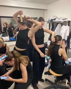 several women in black outfits are doing hair and make - up at the same time