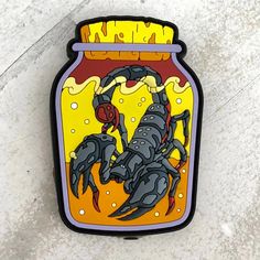 a scorpion in a jar on the ground with yellow and black paint splattered