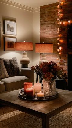 a living room with candles on the coffee table and flowers in vase next to it