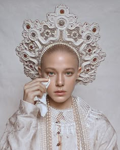 a woman with white makeup and pearls on her head