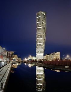 a very tall building sitting next to a body of water in the middle of a city