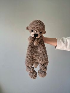 a person holding a stuffed teddy bear in their right hand and the other hand is pulling it up