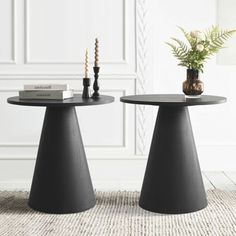 two black tables sitting on top of a rug next to a vase with flowers in it