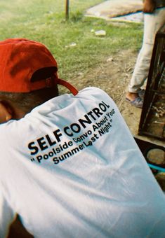 a man wearing a red hat sitting in front of a fire hydrant with the words self control on it