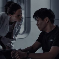 a man and woman sitting next to each other on an airplane looking at something in the distance