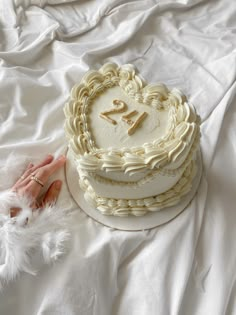 a white cake sitting on top of a bed next to a fluffy pink handbag