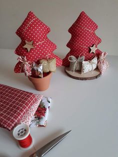 two small christmas trees sitting on top of a table next to a pair of scissors