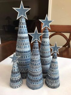 three blue christmas trees with stars on them sitting on a table in front of a chair