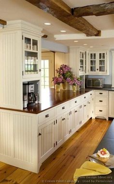 a large kitchen with white cabinets and wood flooring on the counter top, along with an island in the middle