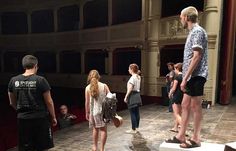 a group of people standing on top of a wooden floor in front of a stage