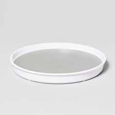 an empty white plate sitting on top of a gray tableclothed floor with no one around it