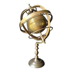 a golden globe on a metal stand against a white background