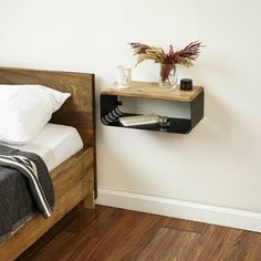 a bed with a wooden headboard and night stand on it next to a white wall