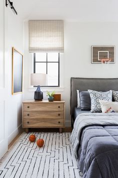 a bedroom with a bed, dresser and basketball on the floor in front of it