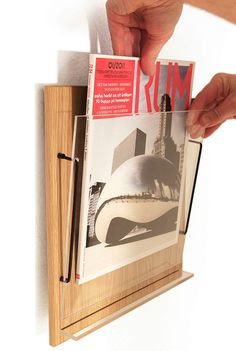 a person is holding up a magazine in front of a wooden frame that holds photos