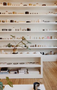 a room filled with lots of white shelves covered in vases and bowls on top of them