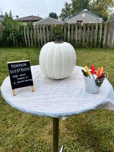 a white pumpkin sitting on top of a table next to a sign that says pumpkin guest book