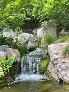 there is a small waterfall in the middle of some rocks and plants on the ground