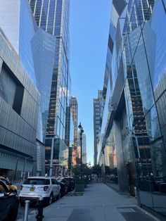 a city street lined with tall buildings next to parked cars on the side of it