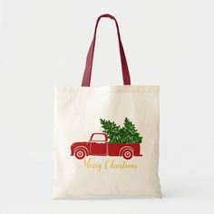 a red truck with a christmas tree on the back is carrying a tote bag