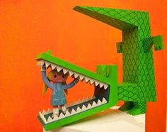 an origami model of a green alligator with its mouth open and tongue out