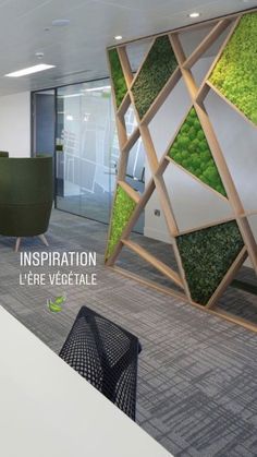 an office cubicle with green plants on the wall and chairs in front of it