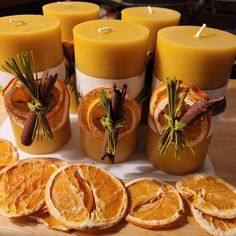 orange slices and cinnamons are arranged on a table next to candles with rosemary sprigs