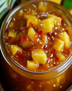 a glass jar filled with pineapple jam on top of a wooden table