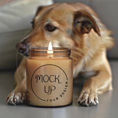 a dog laying next to a candle that says mock up your design on the front