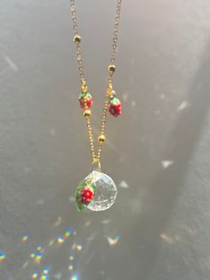 two necklaces that are hanging from a chain with beads on the bottom and one has a glass ball in the middle