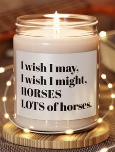 a candle that is sitting on top of a wooden coaster with lights around it and the words i wish i may, i wish i might, horses lots of horses