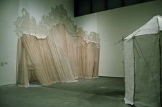 an empty room with sheer curtains on the wall and a white tent in the middle