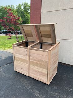 a large wooden box sitting on the side of a building next to a tree and grass