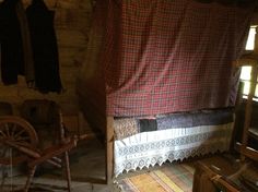 an old fashioned bed in the corner of a room with wooden walls and flooring