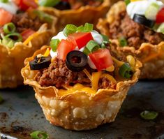 mini taco cups with meat and cheese on top